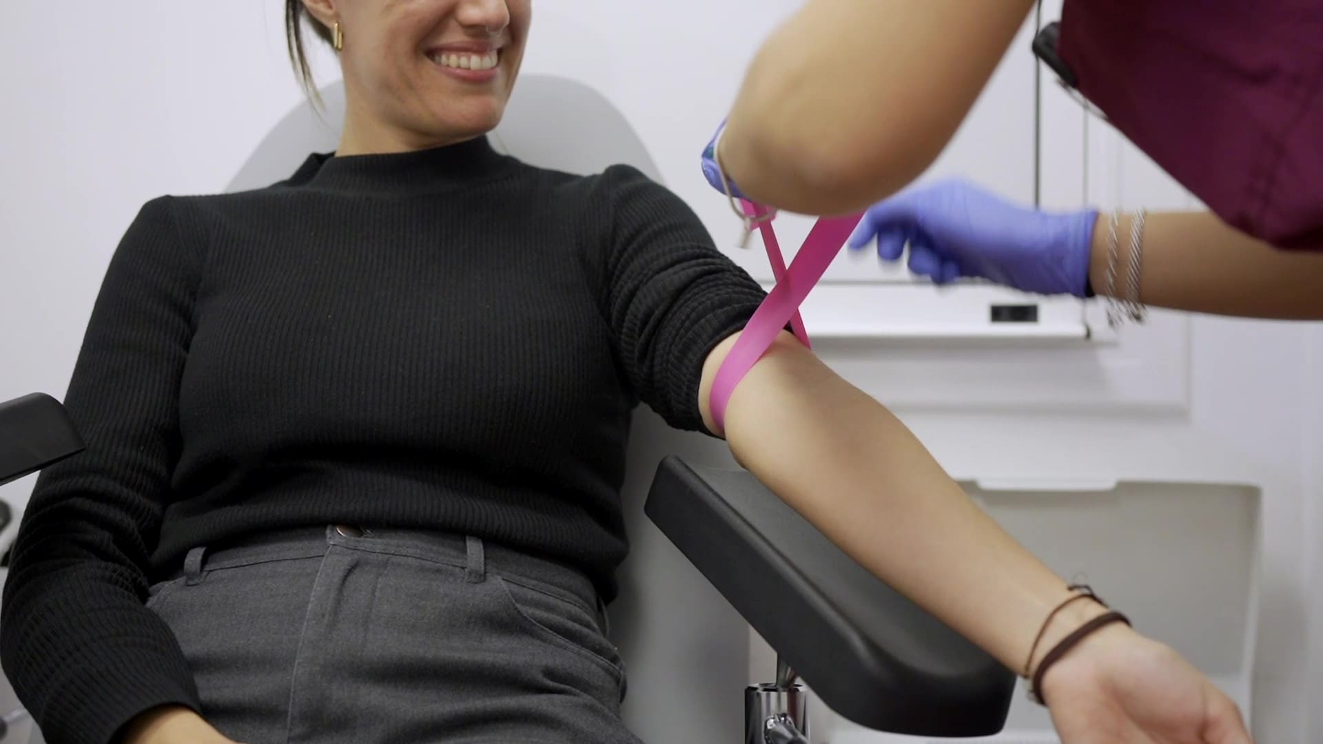 Paziente seduta sul lettino da infermiera con il braccio teso, dove deve essere eseguito un esame del sangue per determinare i livelli di alcuni ormoni. Questo esame viene eseguito durante il trattamento di FIV per monitorare la risposta alla stimolazione ovarica.